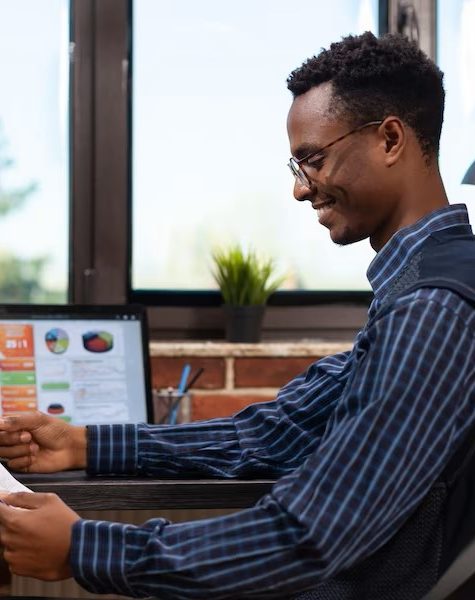 startup-owner-holding-clipboard-with-annual-bussiness-charts-happy-with-turnover-results-sitting-desk-with-laptop-entrepreneur-comparing-key-performance-indica