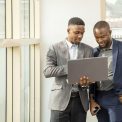 young-businessmen-standing-together-holding-laptop-discussing-business_181624-46531